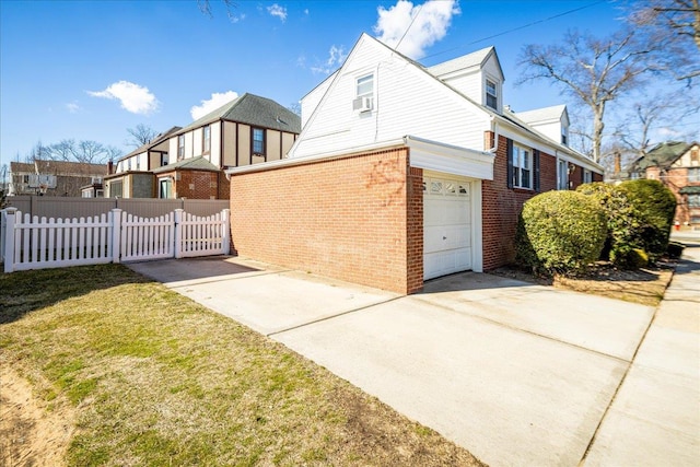 view of side of home featuring a garage, concrete driveway, brick siding, and fence