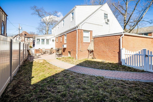 rear view of house featuring a patio area, a fenced backyard, a yard, and brick siding