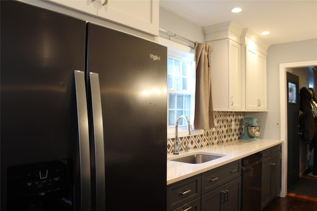 kitchen with dishwasher, a sink, light countertops, refrigerator with ice dispenser, and backsplash