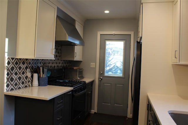 kitchen featuring black appliances, wall chimney exhaust hood, light countertops, and backsplash