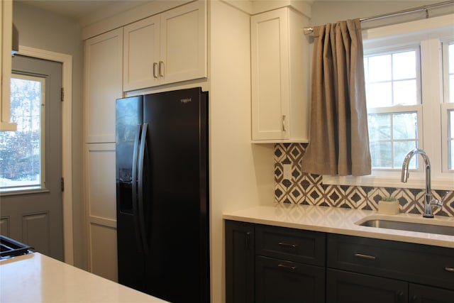 kitchen featuring light countertops, black fridge, a sink, and white cabinets