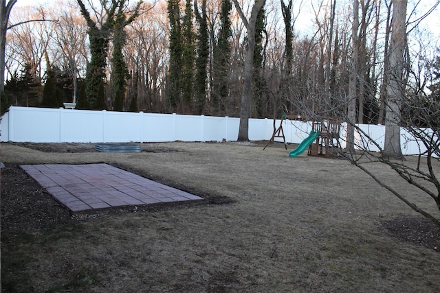 exterior space with a fenced backyard, a playground, and a patio