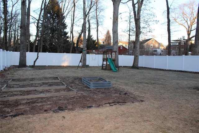 view of yard featuring a fenced backyard, a vegetable garden, and a playground