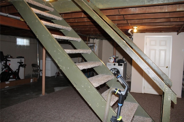 unfinished basement featuring stairs and washer / clothes dryer