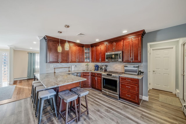 kitchen featuring stainless steel appliances, tasteful backsplash, visible vents, a sink, and a kitchen bar