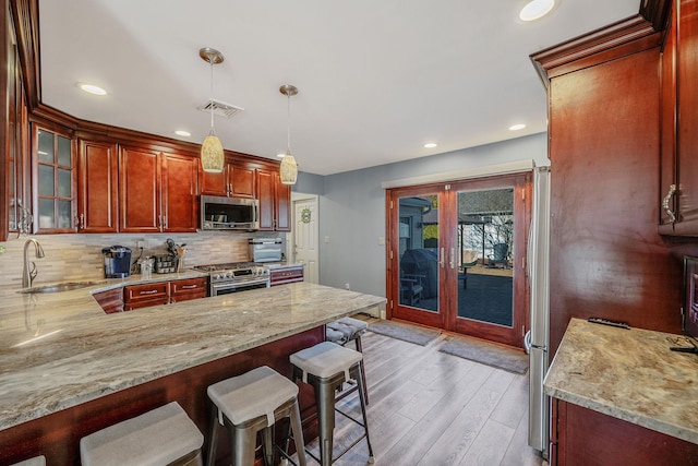 kitchen with french doors, a breakfast bar area, tasteful backsplash, appliances with stainless steel finishes, and a sink