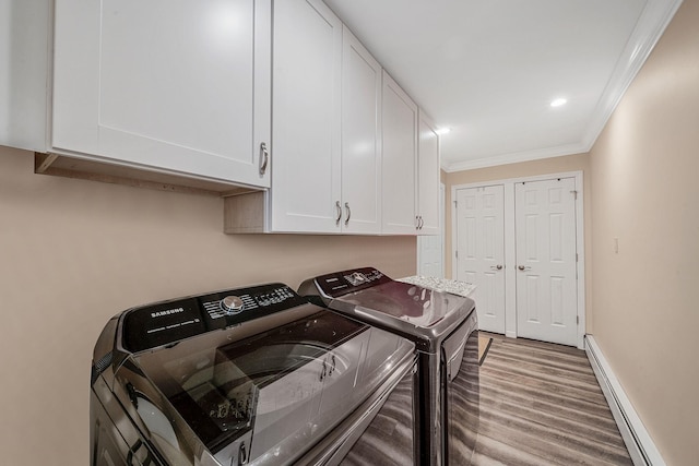 washroom with washing machine and dryer, a baseboard heating unit, wood finished floors, ornamental molding, and cabinet space