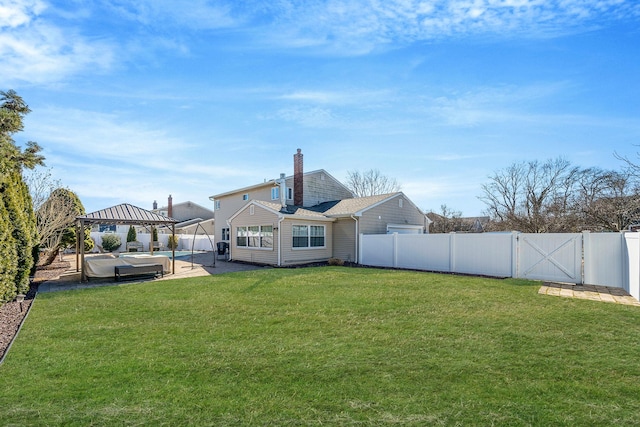 rear view of property featuring a fenced backyard, a gazebo, a yard, a gate, and a chimney