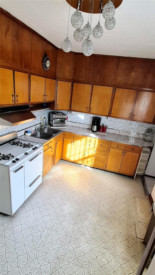 kitchen featuring decorative backsplash, white gas range, light countertops, light floors, and a sink