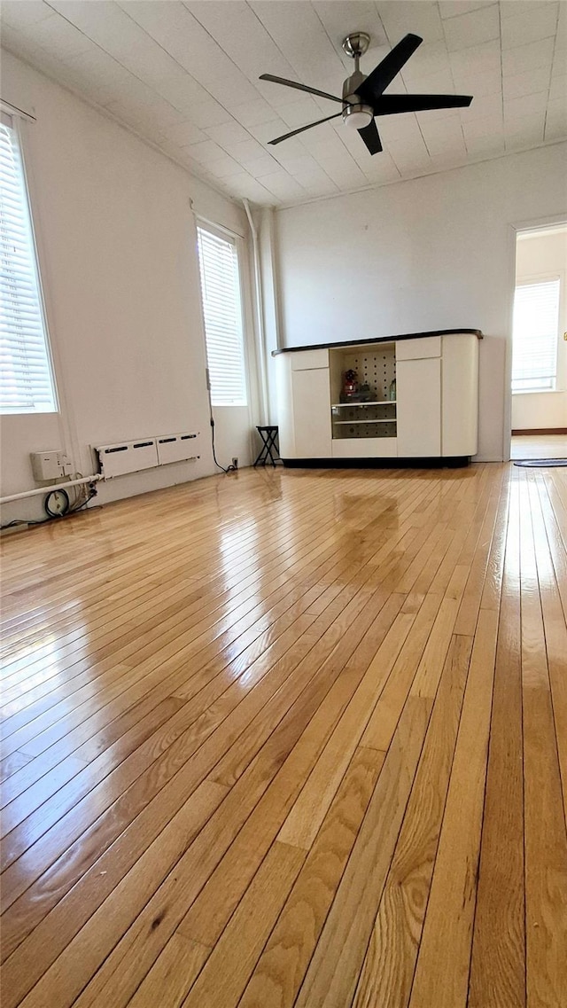 unfurnished living room with ceiling fan, light wood finished floors, and a baseboard radiator