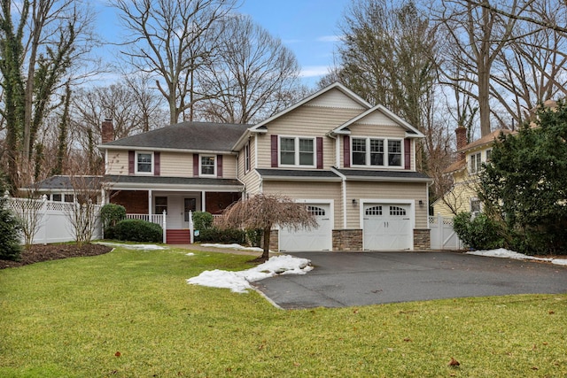 view of front of property featuring a porch, stone siding, driveway, and fence