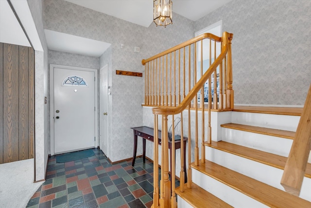 entrance foyer featuring a notable chandelier, stairway, and wallpapered walls