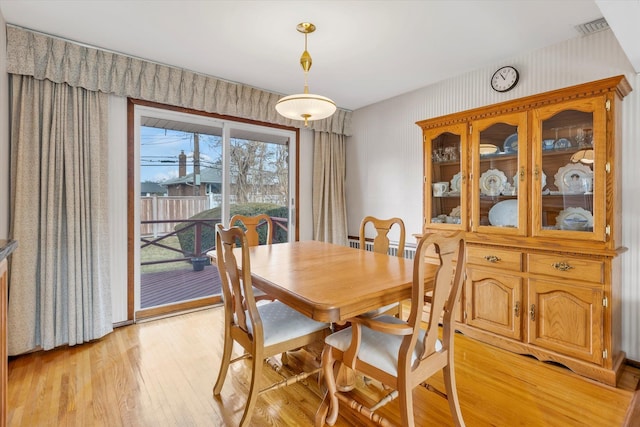 dining area with light wood-type flooring and visible vents