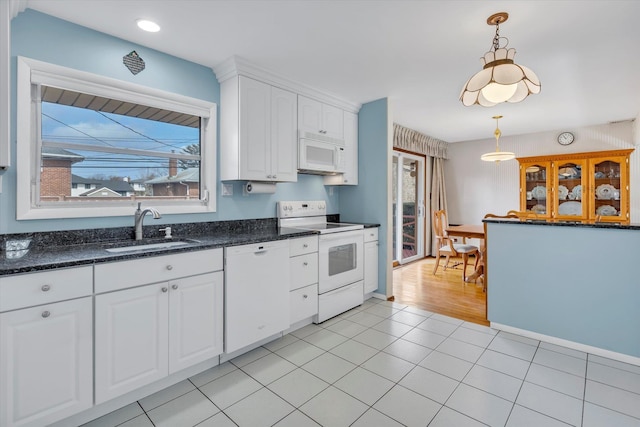 kitchen with white appliances, a sink, a wealth of natural light, and white cabinets