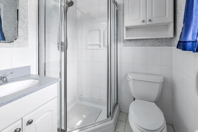 full bath featuring toilet, a stall shower, vanity, and tile walls