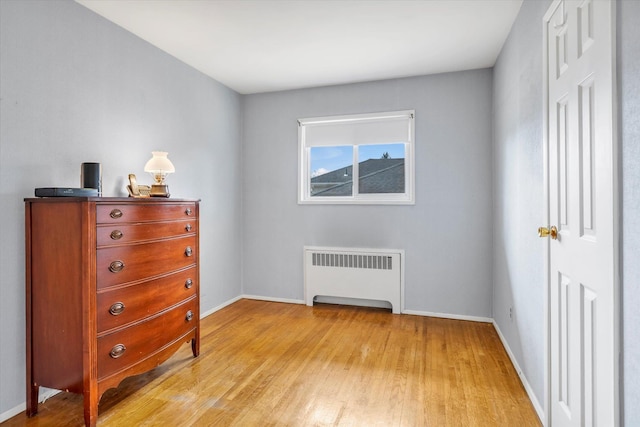 bedroom featuring light wood-style floors, radiator, and baseboards