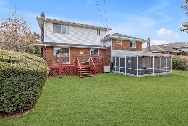 rear view of property featuring a deck, brick siding, a sunroom, a yard, and a chimney