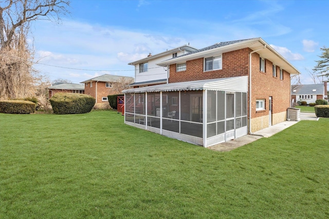 back of house with a sunroom, a lawn, and brick siding