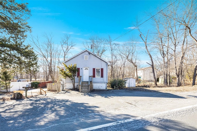 view of front of home with fence, a storage unit, and an outbuilding