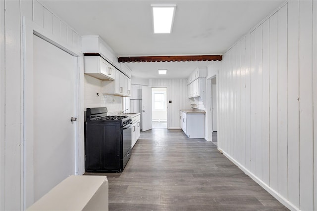 kitchen featuring dark wood-style flooring, white cabinetry, baseboards, light countertops, and gas stove