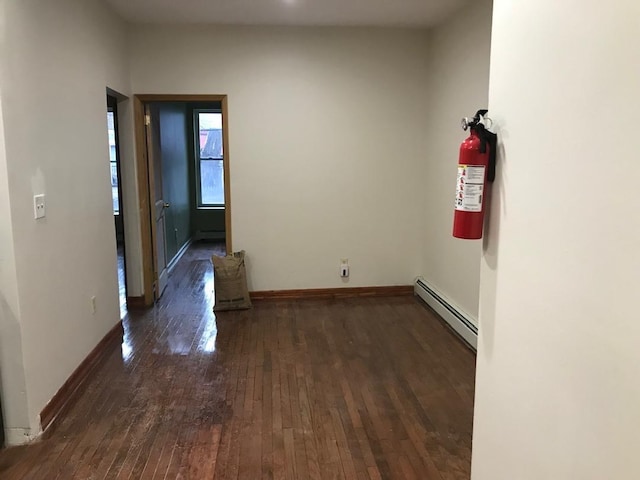 unfurnished room featuring dark wood-style floors, baseboards, and baseboard heating