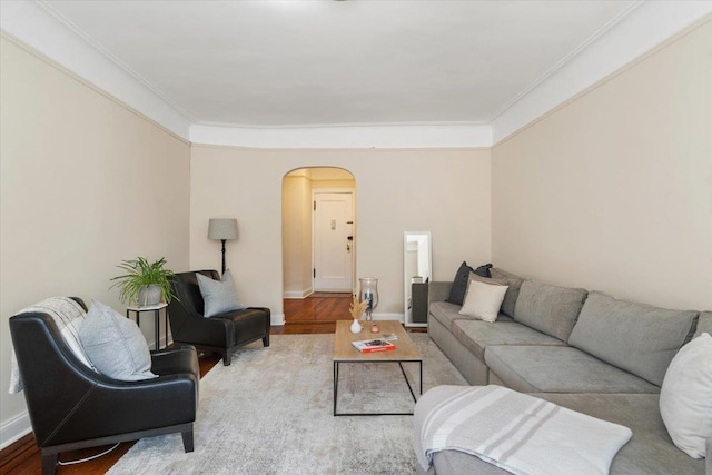 living room with arched walkways, ornamental molding, wood finished floors, and baseboards