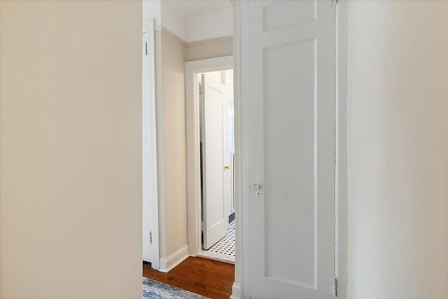 hall featuring dark wood-type flooring and baseboards