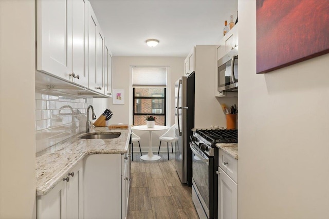 kitchen with white cabinets, appliances with stainless steel finishes, decorative backsplash, and a sink