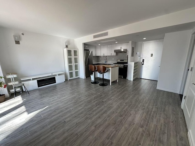 unfurnished living room with dark wood-style flooring, a fireplace, visible vents, and recessed lighting