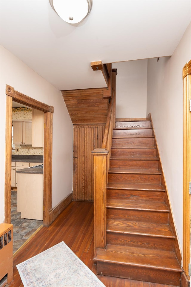 stairs with radiator, baseboards, and wood finished floors