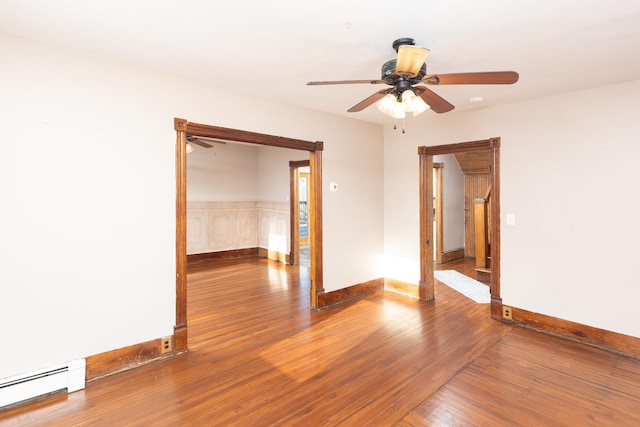 empty room with a baseboard heating unit, hardwood / wood-style floors, a ceiling fan, and baseboards