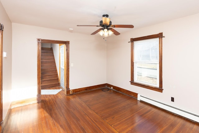 empty room featuring a baseboard radiator, stairway, a ceiling fan, baseboards, and hardwood / wood-style flooring