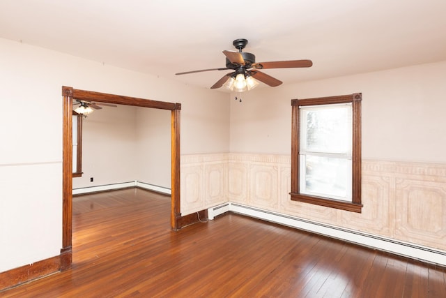 spare room featuring a baseboard heating unit, ceiling fan, and dark wood finished floors