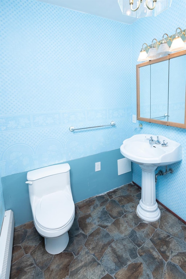 bathroom featuring radiator, stone finish floor, a notable chandelier, and toilet