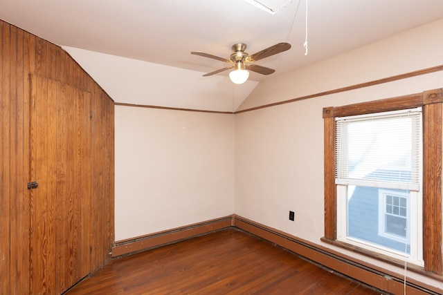 spare room featuring a baseboard heating unit, a ceiling fan, vaulted ceiling, and wood finished floors