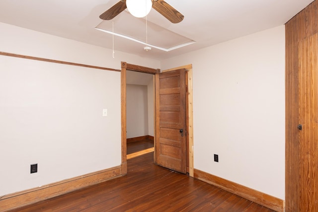 empty room with a ceiling fan, attic access, baseboards, and wood finished floors