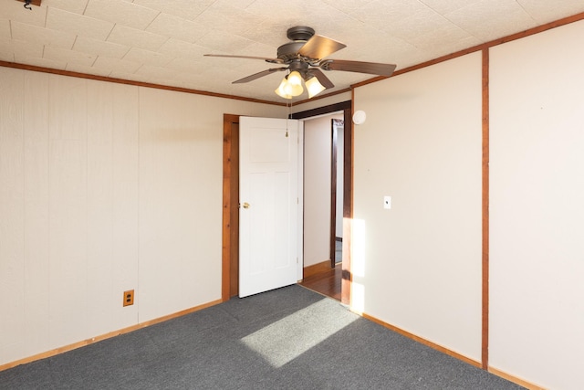 carpeted spare room with ornamental molding, ceiling fan, and baseboards