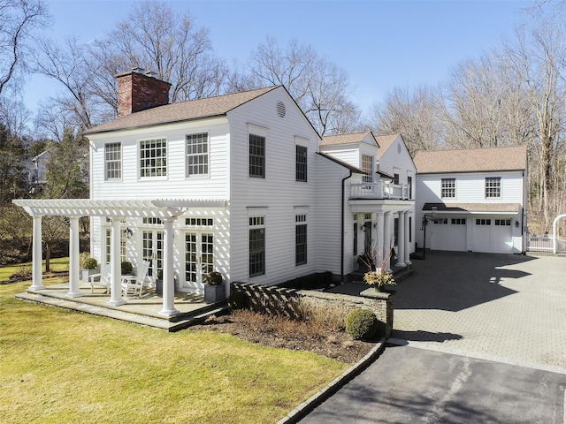 view of front of property with aphalt driveway, french doors, a pergola, a chimney, and a front yard