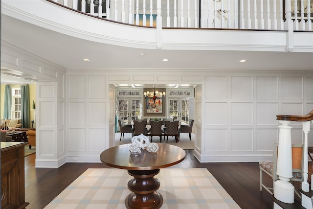 interior space with dark wood-type flooring, recessed lighting, a decorative wall, and an inviting chandelier