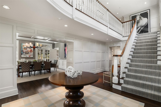 interior space featuring recessed lighting, a decorative wall, a high ceiling, wood finished floors, and stairs