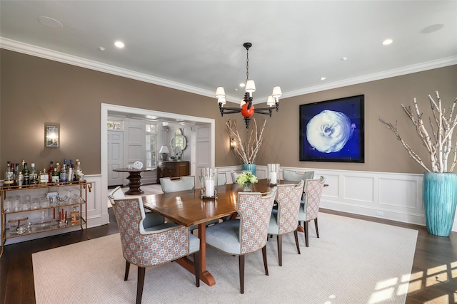 dining room featuring ornamental molding, wainscoting, wood finished floors, and an inviting chandelier