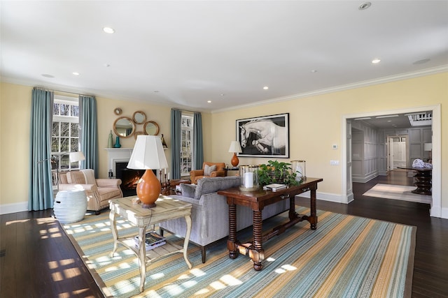 living area featuring baseboards, wood-type flooring, a lit fireplace, crown molding, and recessed lighting