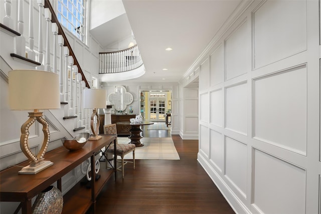 hallway featuring stairs, plenty of natural light, dark wood finished floors, and a decorative wall