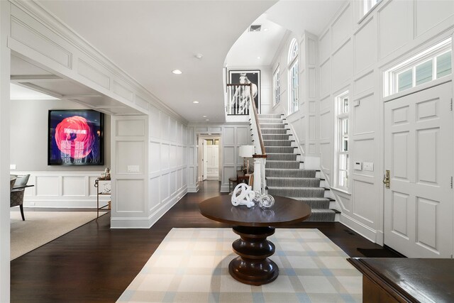 entryway featuring visible vents, stairway, ornamental molding, dark wood-style flooring, and a decorative wall