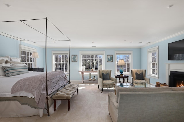 bedroom with light carpet, a lit fireplace, baseboards, and crown molding