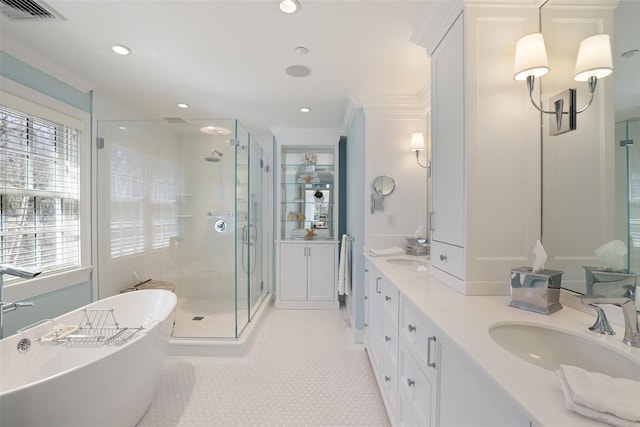 full bath featuring double vanity, a stall shower, visible vents, a freestanding bath, and a sink