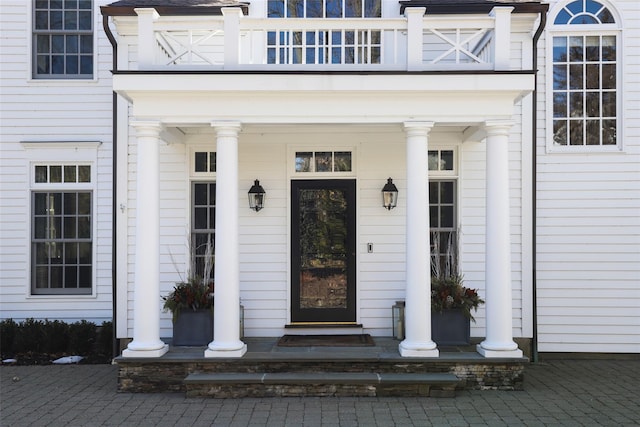 entrance to property featuring covered porch and a balcony