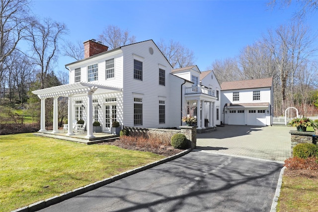 view of front of home with a front lawn, a pergola, a garage, a balcony, and a chimney