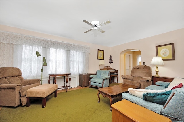 carpeted living room featuring arched walkways and a ceiling fan