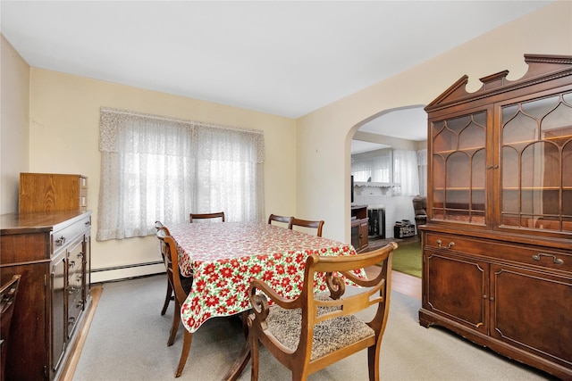 dining area with carpet, arched walkways, and baseboard heating